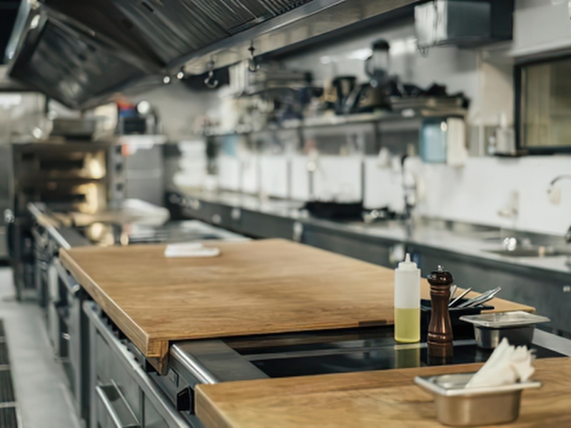 A commercial kitchen featuring stainless steel countertops, butcher block counters, and other modern cooking equipment.