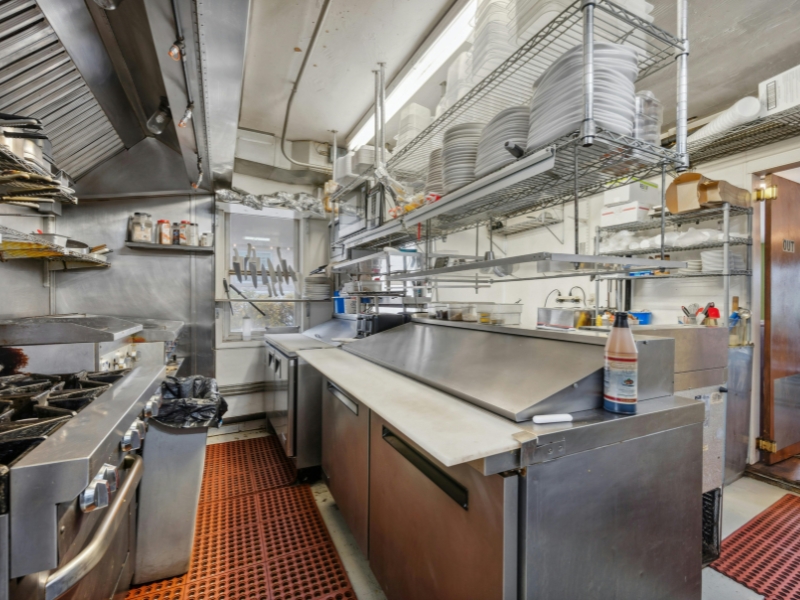 A commercial kitchen made up of multiple stainless steel appliances, counters, and workspaces.