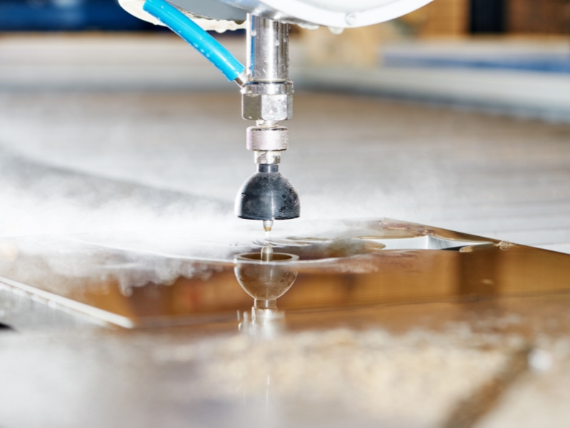 An image of a water jet cutting machine cutting a piece of stainless steel.
